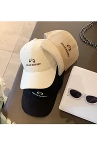 Detailansicht von drei bestickten Baseballcaps in Schwarz, Creme und Hellbraun.