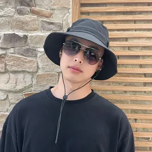 Stylischer asiatischer Mann trägt schwarzen Outdoor-Sonnenhut mit breiter Krempe und Band