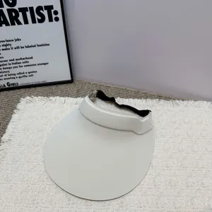 Detailansicht einer cremefarbenen Sonnenblende mit breiter Krempe und schwarzem Gummiband.