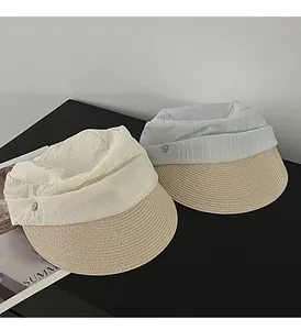 Detail of two pleated straw sun hats in white and grey, equestrian style on black