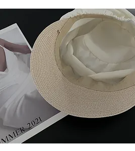 Close-up detail of a pleated straw sun hat interior showing fabric texture and band