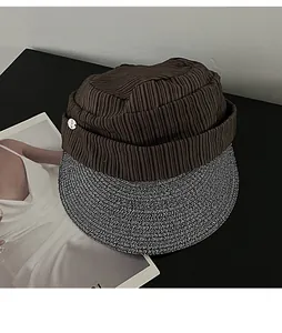 Detailed view of the unique pleated brown fabric crown and woven straw brim sun hat