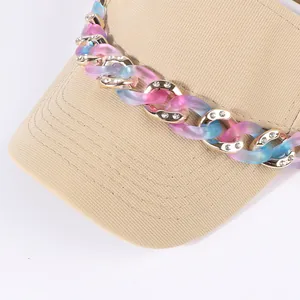 Dettaglio della visiera kaki con catena decorativa con strass rosa e blu sfumati