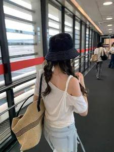Vista trasera de una mujer con un sombrero de pescador de mezclilla azul con costuras