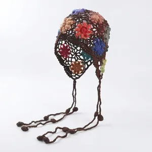 Detailed macro shot of bohemian crochet flower hat featuring handmade knit and tassels