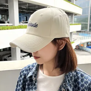 Side profile close-up of a model wearing a beige minimalist embroidered baseball cap outdoors