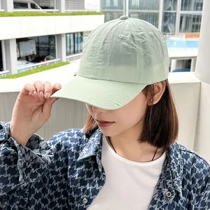Close-up of a female model wearing a light green quick-dry baseball cap outdoors.