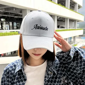 Close-up of light blue baseball cap with Attitude embroidery on a female model