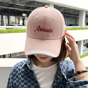 Close-up of pink baseball cap with Attitude embroidery worn by a model in outdoor setting