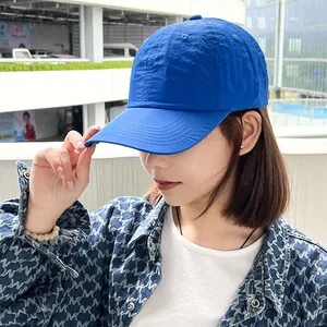 A close-up side view of a woman wearing a vibrant blue quick-dry baseball cap outdoors