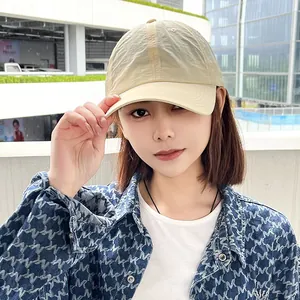 Close-up of a beige quick-dry baseball cap worn by a model in a bright urban setting.