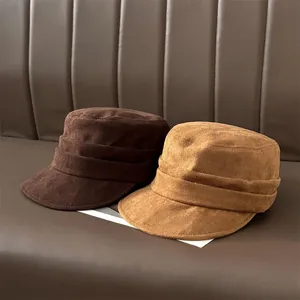 Pleated suede newsboy hats in brown and tan shown on a textured leather background