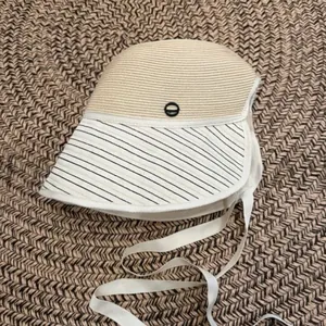 Close-up view of a stylish summer straw bucket hat featuring a striped brim and ribbon ties