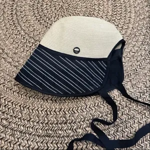 Detailed view of a navy striped sun hat with a cream crown and elegant ribbon tie.