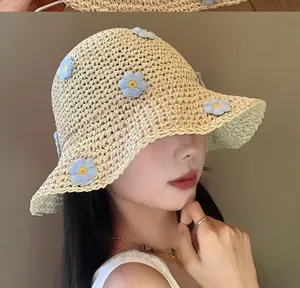 Primo piano di un cappello di paglia con fiori blu per la protezione solare estiva al mare.