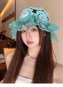 Detailed view of a mint green crochet beanie with lace edge worn by a female model.