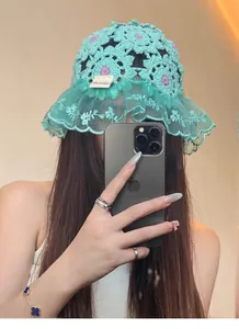 Close-up of a handmade teal crochet floral beanie featuring an elegant lace ruffle brim