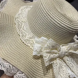 Primo piano di un cappello di paglia beige da donna con pizzo bianco e fiocco decorativo