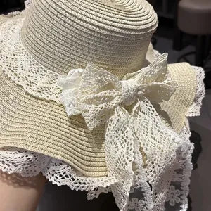 Dettaglio di un fiocco in pizzo bianco su un cappello di paglia estivo a tesa larga.