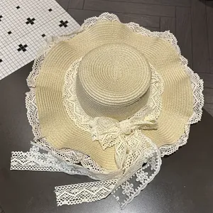 Dettaglio ravvicinato di un cappello di paglia beige con fiocco in pizzo e bordi smerlati