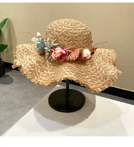 Close-up detail of a hand-woven straw sun hat featuring vibrant floral decorations