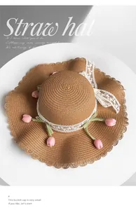 Detailed top view of a woven straw sun hat with pink tulip and white lace accents