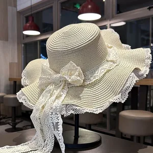 Elegante cappello di paglia a cima piatta con fiocco in pizzo bianco e tesa larga da spiaggia