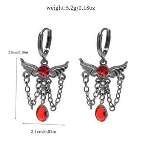 Detail shot of gothic wing earrings featuring red gemstones and hanging chain tassels
