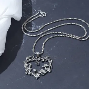 Close-up of heart-shaped necklace featuring intricate mushroom and floral vine details.
