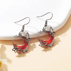 Detailed view of red blood moon earrings with silver butterfly accents in a gothic style.
