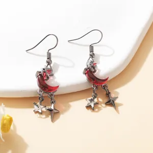 Close-up of gothic blood red crescent moon earrings with dangling silver star charms