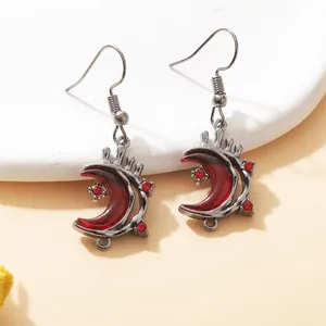 Detail of gothic gunmetal moon earrings with deep red resin and sparkling rhinestones