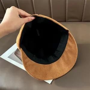 Detail view of the black interior lining and sweatband of a brown suede newsboy hat
