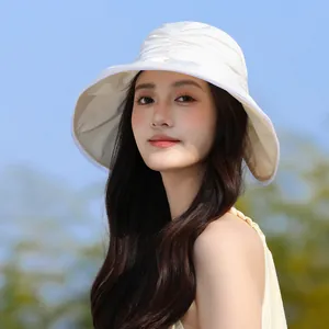 Elegant white pleated bucket hat with mesh details worn by a model for sun protection.