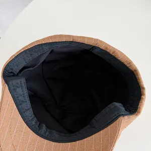 Détail de la doublure intérieure noire d'une casquette gavroche rétro à rayures marron
