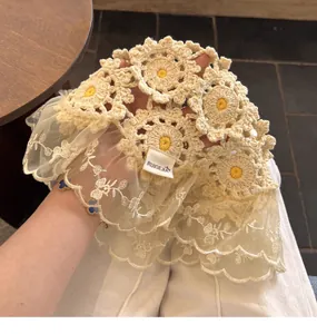Detail of hand-crocheted floral beanie with delicate lace edging and brand label