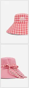 Vista detallada de un sombrero de pescador reversible a cuadros rojos con lazo decorativo