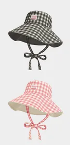 Vista detallada de sombreros bucket de cuadros vichy con lazos en color negro y rosa.