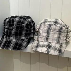 Close-up detail of vintage British pleated newsboy caps with black and white plaid patterns