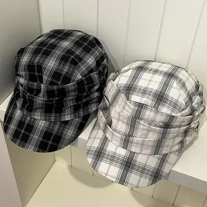 Macro view of retro pleated plaid newsboy caps in black and white colors on a shelf.