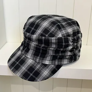 Close-up of a retro black and white plaid newsboy cap with elegant pleated side details.