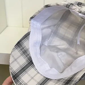 Internal details of a plaid newsboy hat showing white lining and adjustable strap