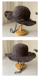 Close-up of a breathable dark grey outdoor sun hat with wide brim on a wooden stand