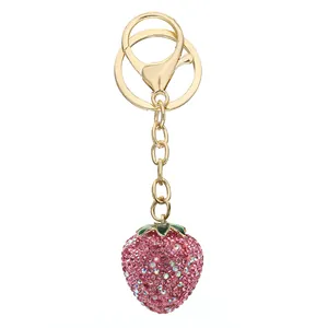 Detailed macro view of pink rhinestone strawberry keychain with gold hardware finish