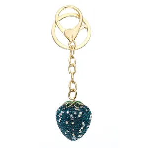 Detailed macro shot of a dark teal rhinestone-encrusted strawberry keychain with gold clasp