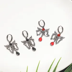 Macro detail of gothic wing earrings featuring red and black crystal drop pendants