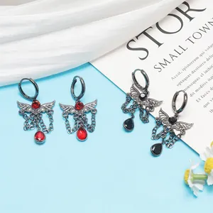 Close-up of Gothic wing earrings with blood moon red and black teardrop stones