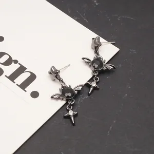 Detailed macro view of punk style star and cross drop earrings with black gemstones