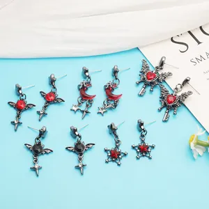 Detailed view of gothic red gem earrings set with butterfly and moon pendants