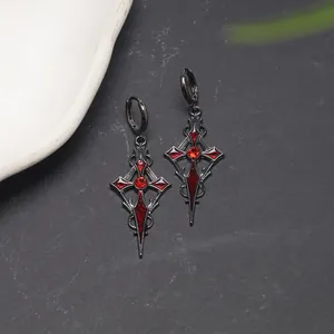 Close-up detail of gothic black dagger earrings featuring vibrant red crystal gems